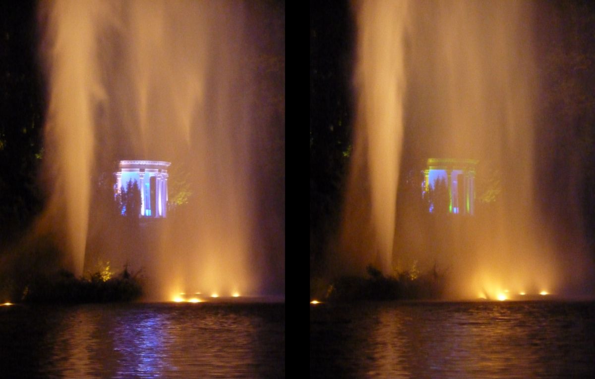 Der Apollo-Tempel am Fontänenteich wird mit wechselnden Farben angestrahlt, die durch die Fontäne hindurch zu sehen sind.